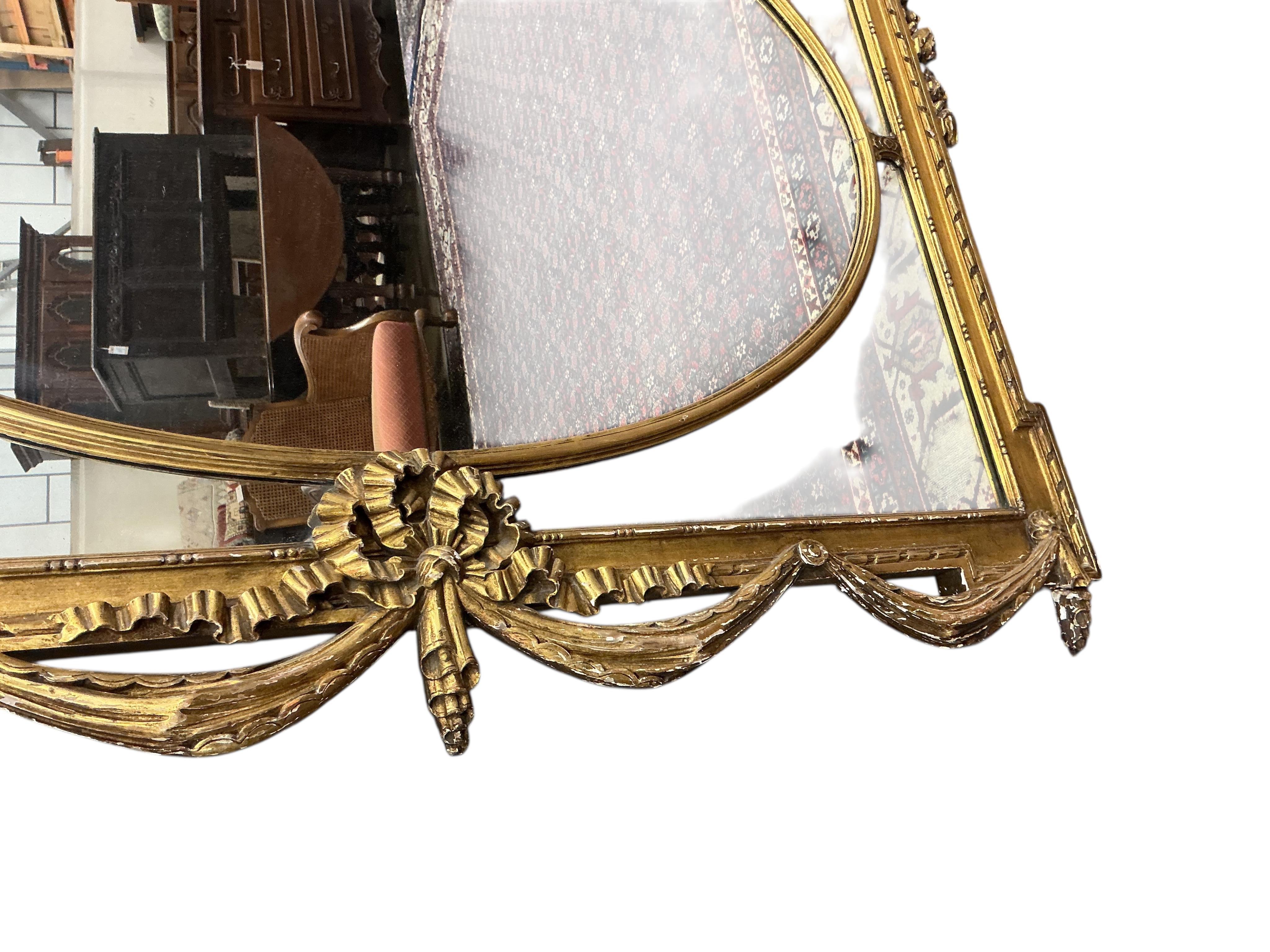 A Victorian style giltwood and composition overmantel mirror with cross torch and quiver crest, width 136cm, height 110cm